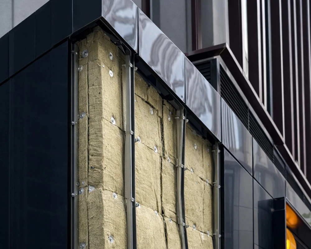 Close-up of an exposed building façade showing insulation panels, fixings, and metal framing prior to external cladding installation